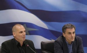 Outgoing Greek Finance Minister Yanis Varoufakis, left, speaks as the new Finance Minister Euclid Tsakalotos listens to him during a hand over ceremony in Athens, Monday, July 6, 2015. Following Sunday's referendum the Greece and its membership in Europe's joint currency faced an uncertain future Monday, with the country under pressure to restart bailout talks with creditors as soon as possible after Greeks resoundingly rejected the notion of more austerity in exchange for aid. (ANSA/AP Photo/Petr David Josek)