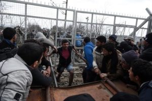 Refugees and migrants try to broke an iron fence from the Greek side of the border as Macedonian police stand guard, near the northern Greek village of Idomeni on Monday, Feb. 29, 2016. No arrests or injuries were reported. About 6,500 migrants are stuck on the Greek-Macedonian border at Idomeni, waiting to travel north, but Macedonia is only admitting a trickle. (ANSA/AP Photo/Giannis Papanikos)