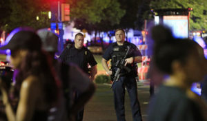 DALLAS, TX - JULY 7: Dallas police and residents stand near the scene where four Dallas police officers were shot and killed on July 7, 2016 in Dallas, Texas. According to reports, shots were fired during a protest being held in downtown Dallas in response to recent fatal shootings of two black men by police - Alton Sterling on July 5, 2016 in Baton Rouge, Louisiana and Philando Castile on July 6, 2016, in Falcon Heights, Minnesota. Ron Jenkins/Getty Images/AFP